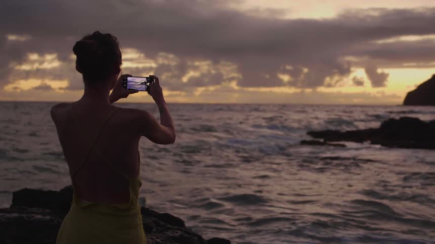 A woman is taking pictures at the beach