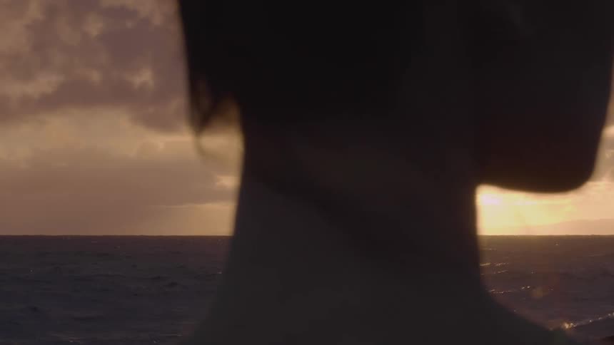 A woman standing on the shore looking out at the water