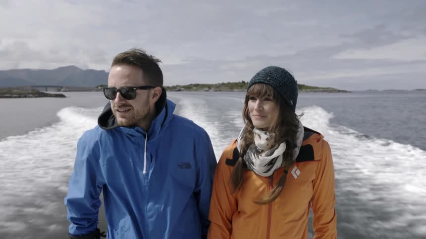 A couple standing on a boat as it speeds across the water