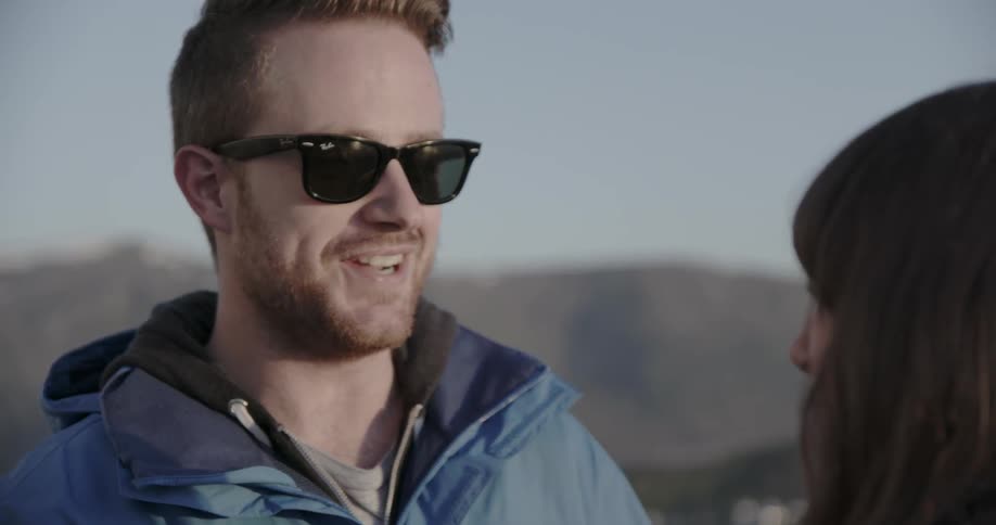 A man in sunglasses talks to a woman