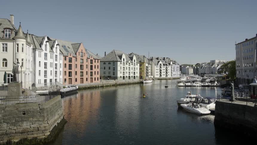 A kayak going down a river lined with tall houses