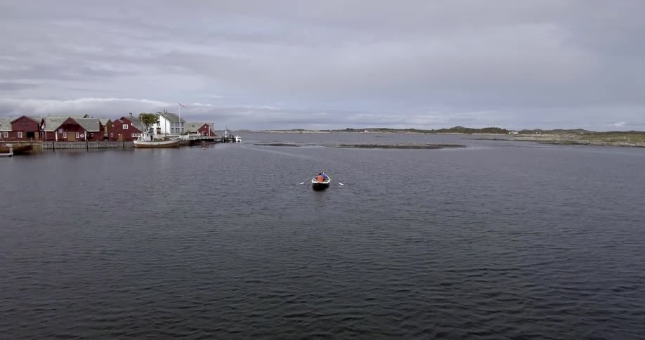 A person paddles a boat near an island