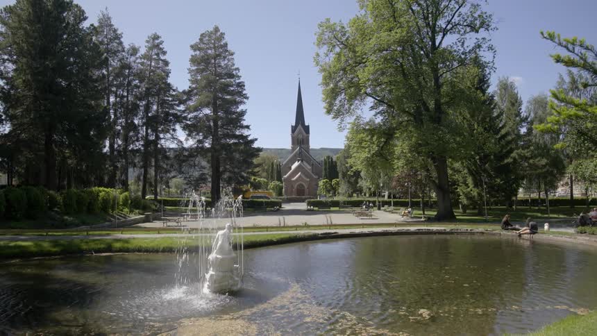 A fountain flows in a park across from a church