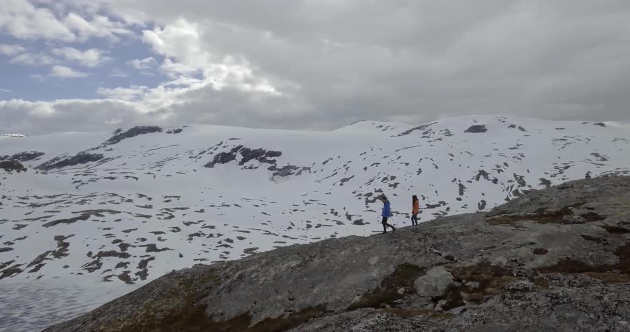 A man and woman walk across a rocky area