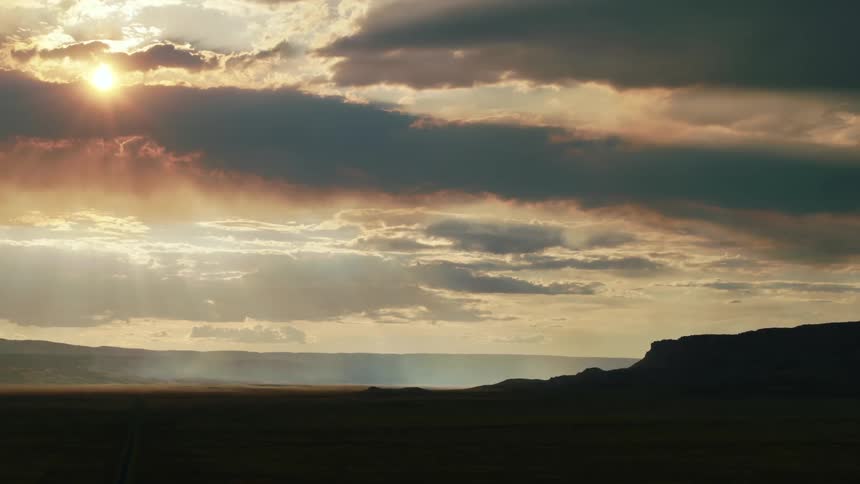 The sun shining through clouds over a desert