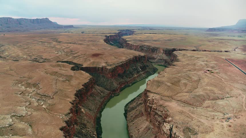 A murky river running along the bottom of a canyon on a cloudy day
