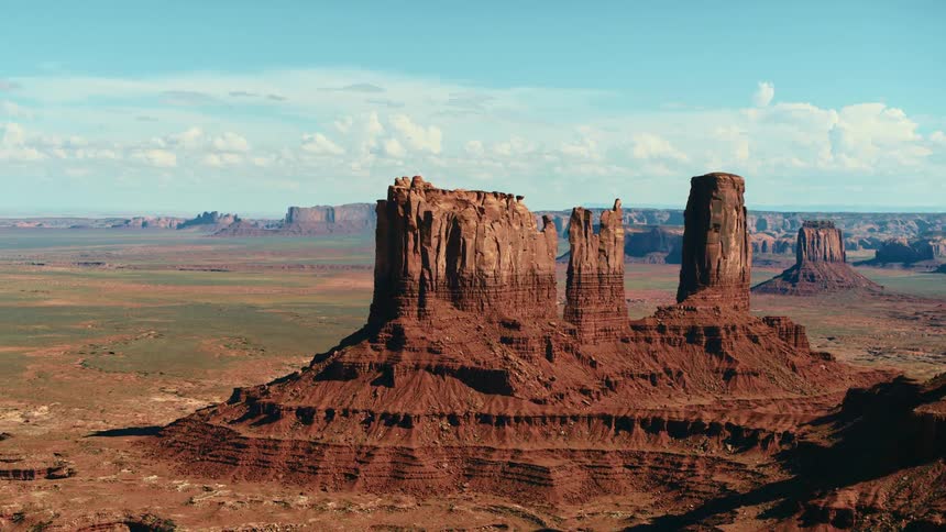 An aerial view of red rock formations in a desert in the daytime