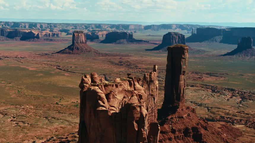 Mesa stand among plains leading to mist covered horizon under cloudy sky