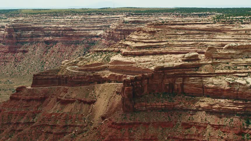 A dirt road runs through the red rock canyons and surrounding greenery