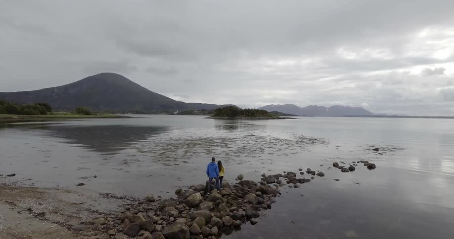 Two people are standing on some rocks by the water