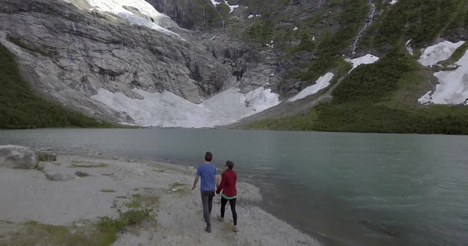 A man and a woman walk next to a lake