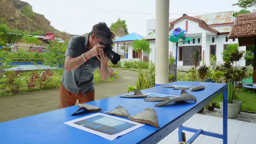 A man takes photos of shark fins on a table outdoors