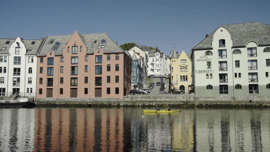 A canoe is being rowed in front of some homes by a canal