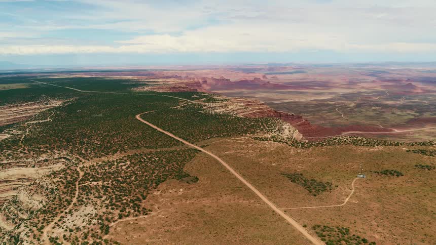 Narrow roads and trails run through a rural field that leads to a canyon