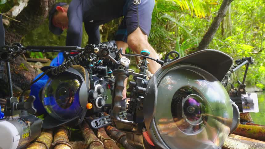 Man unpacks bag setting device near underwater camera on bamboo platform