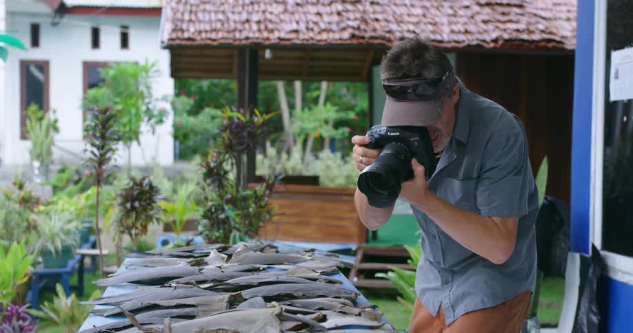 Man taking photos of shark fins on table outdoors