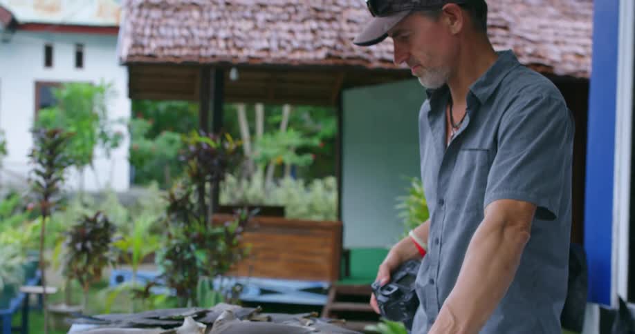 A man standing by a table with shark fins with buildings and trees in the background