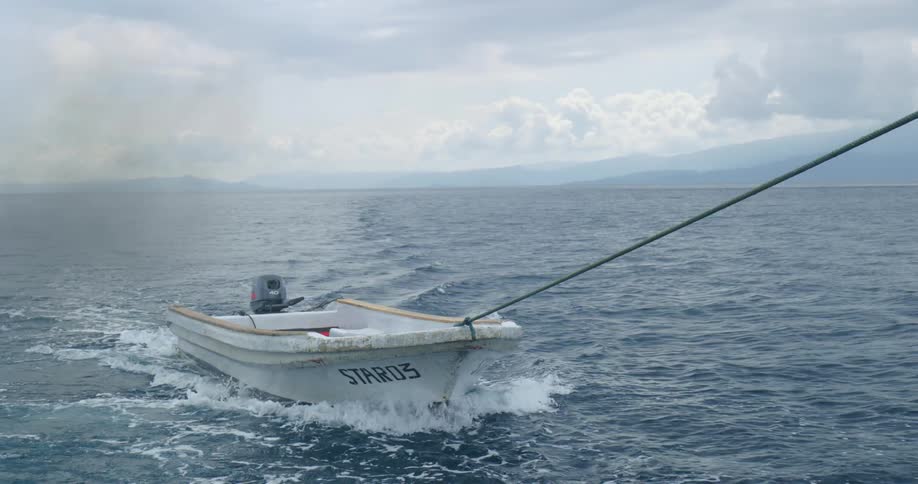 A small boat is towed across a lake