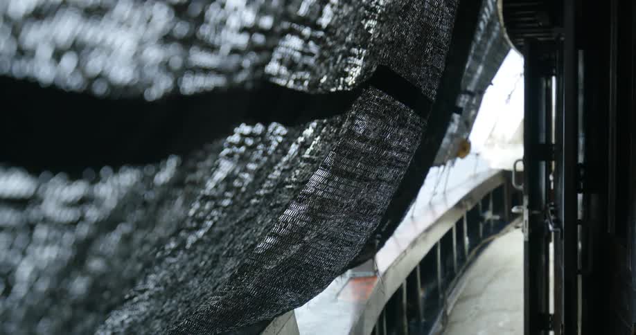 Curtain obscures view of passing water as rain falls onto deck
