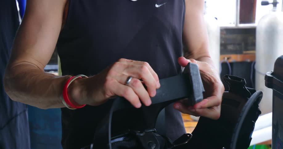 A man prepares some scuba diving equipment by adjusting its straps