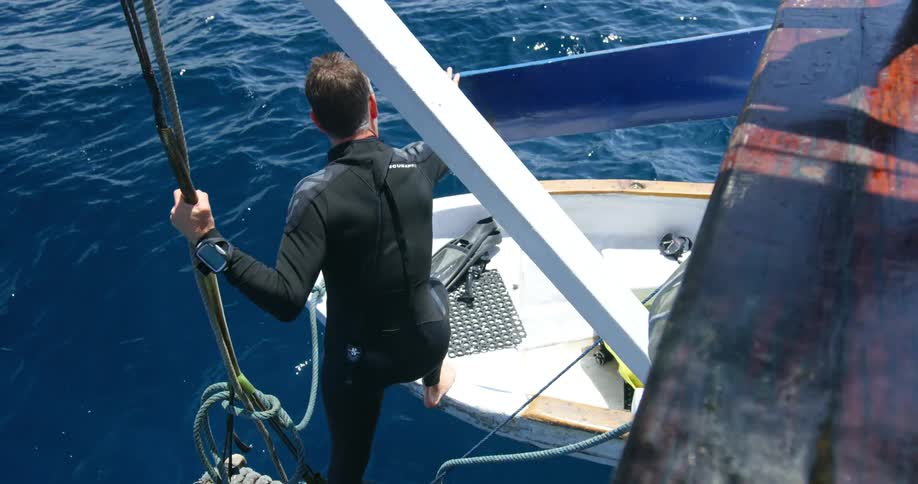 A man steps from a platform to a small boat floating in the water
