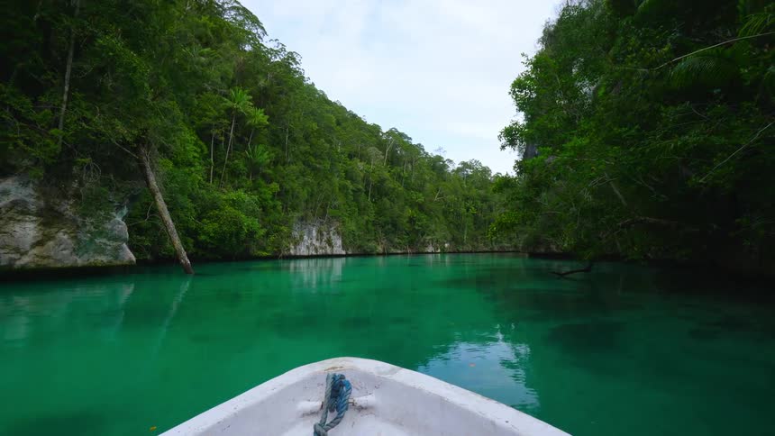 A boat floating on turquoise river water in a jungle