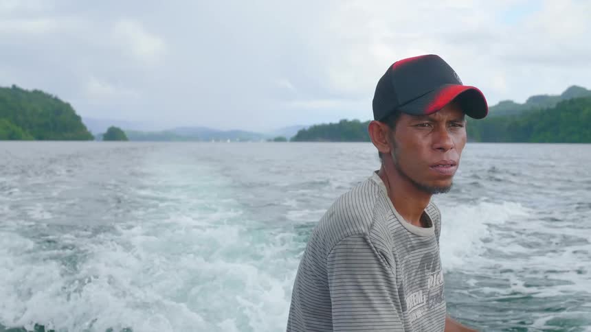A man on a boat in the water with waves as the boat drives