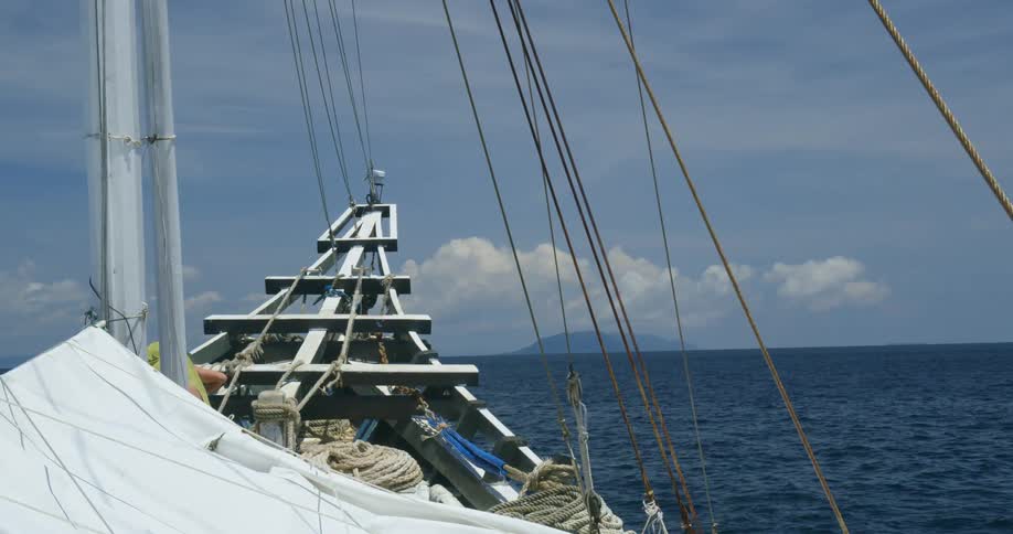 Piles of rope sit on the bow of a sailboat anchored in the ocean