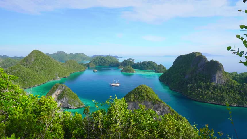 A ship floating on turquoise ocean water off a tropical coast