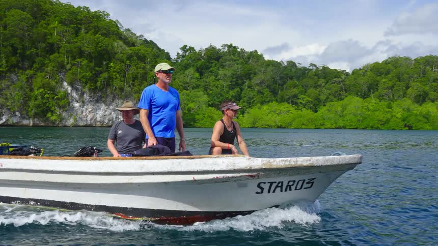 A group of aging men ride a motorboat across the ocean during the day