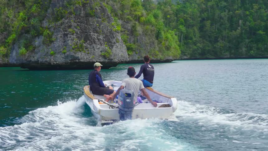 Three men on a boat with land trees the sky and clouds in the background