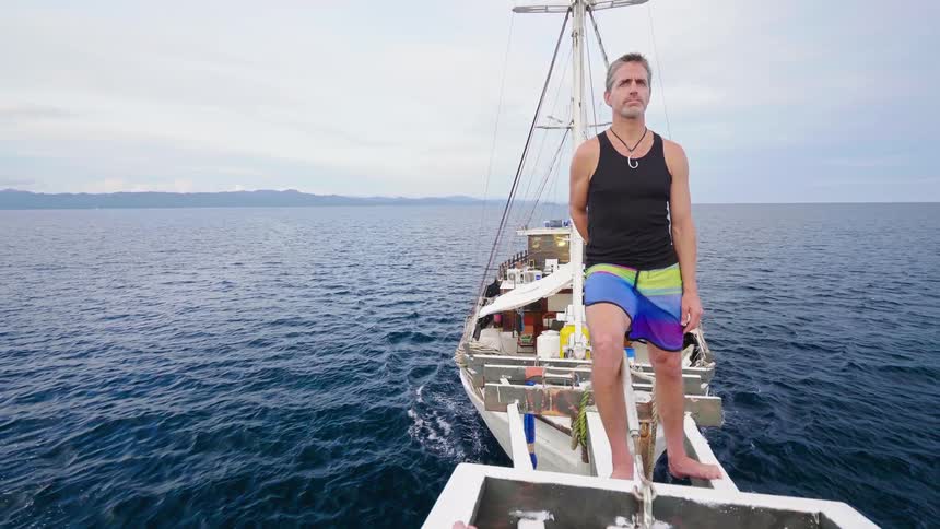 Man stands on sailboat in ocean