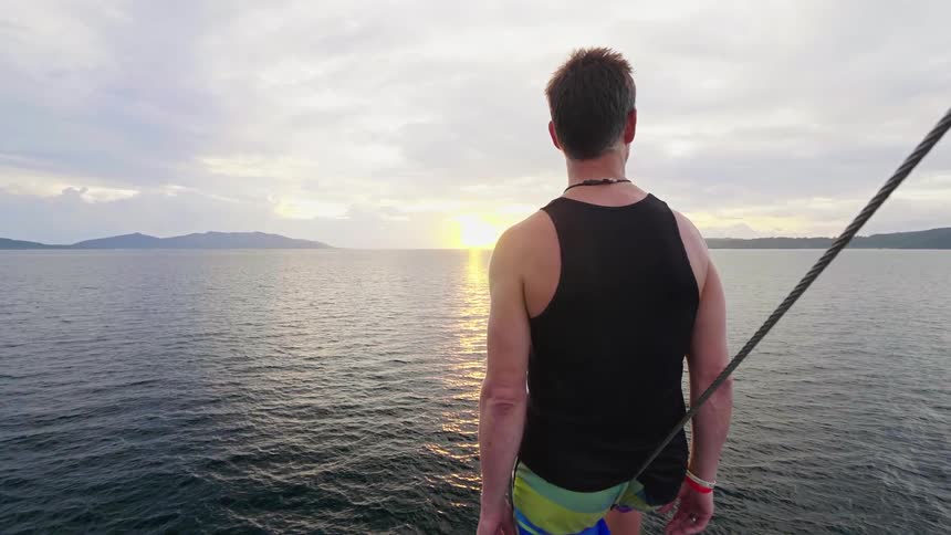 A man standing on a boat with the sky and clouds in the background