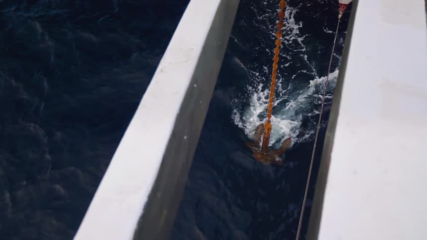 An anchor dragging next to a boat in the ocean