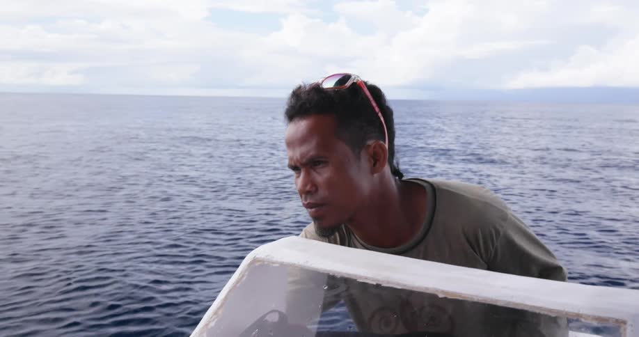A man standing on a boat with the sky and clouds in the background