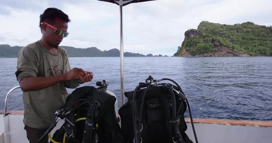A man on a boat adjusts scuba equipment