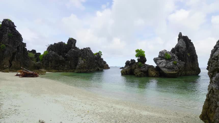 Water rippling on a sandy beach with rock formations scattered around