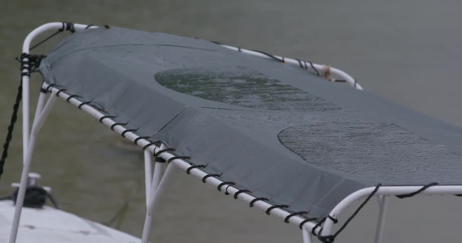 A view of rain falling on the top of a boat on a lake