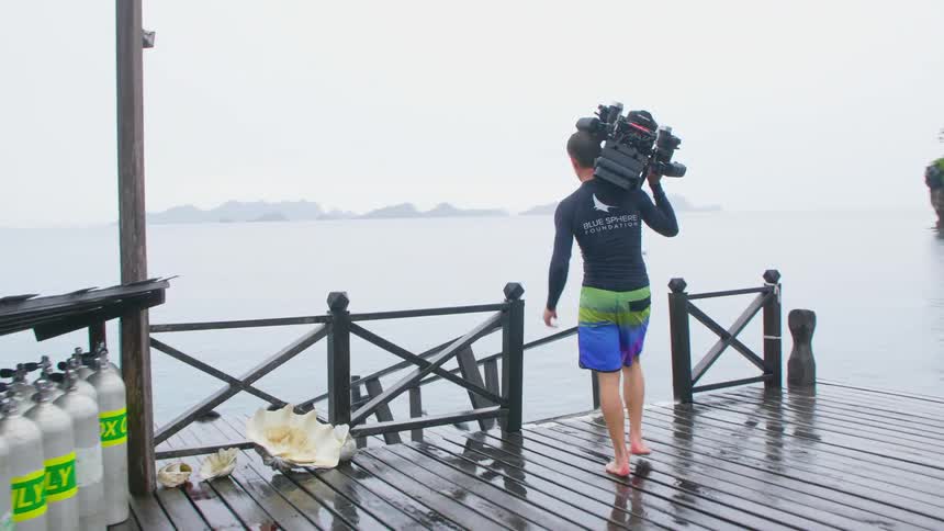 A man carrying scuba gear down to a boat