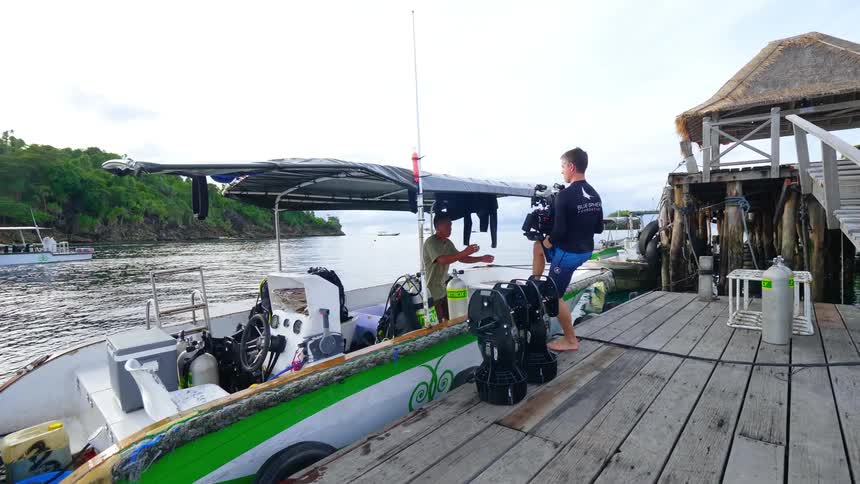A man carefully walks down a ramp on a boat dock while carrying a submersible digital video camera