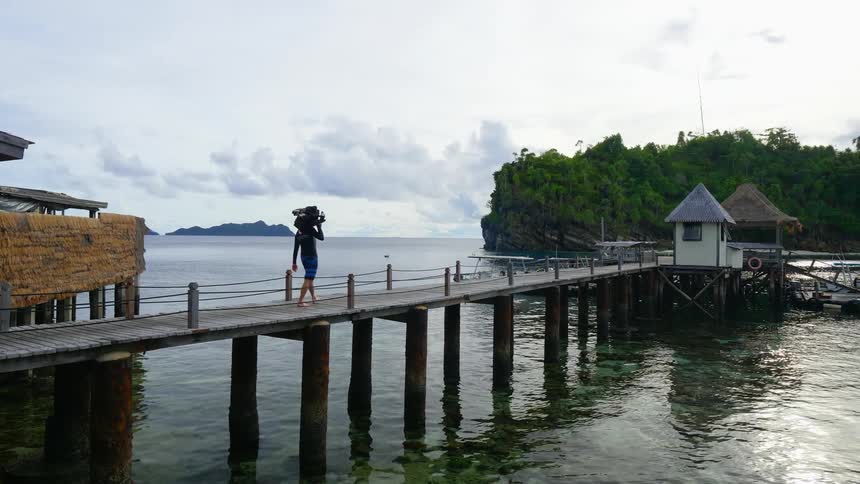 A male walking on a pier carrying items