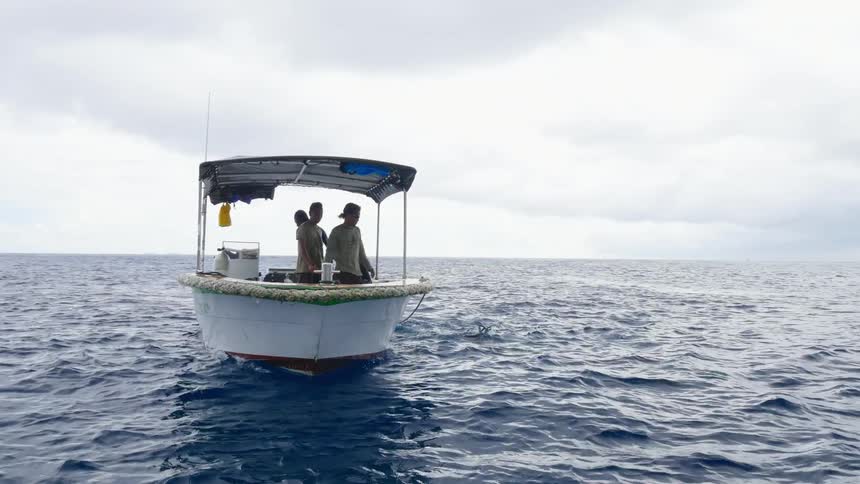 Three men are sailing on a boat in the ocean