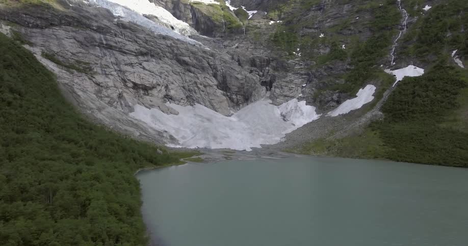 A mountain lake is ringed by trees and snow covered rock