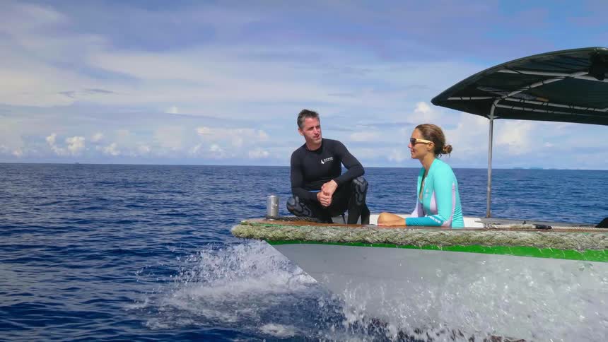 Two people ride on a boat in a large open waterway