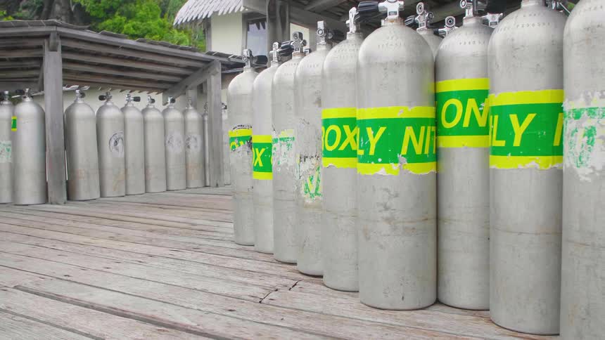 Oxygen tanks resting on a wooden floor with a building and trees in the background