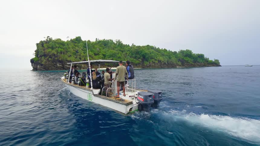 Groups of people on tour boats leave the shore to go scuba diving