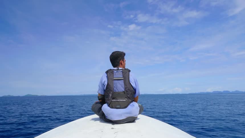 A ranger on a patrol boat on the bow of a boat as it crosses the ocean on a sunny day