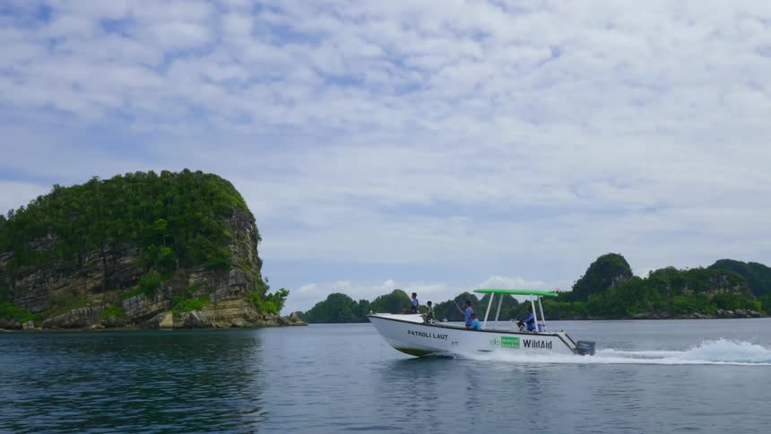 Men hold up fishing rods as they ride in a speedboat in the ocean