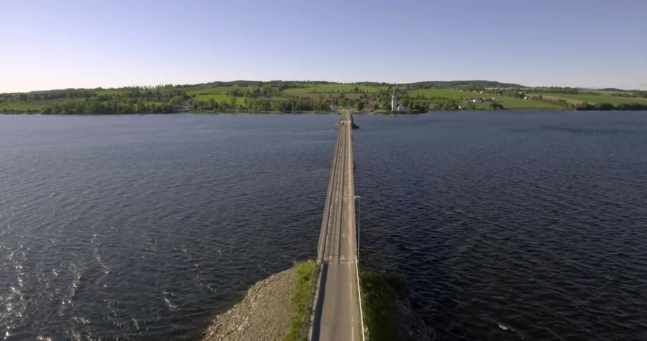 A low bridge over a large flowing lake and a distant shore