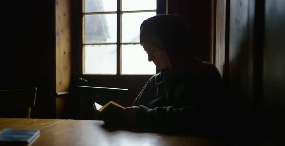 A man is sitting indoors and reading a book